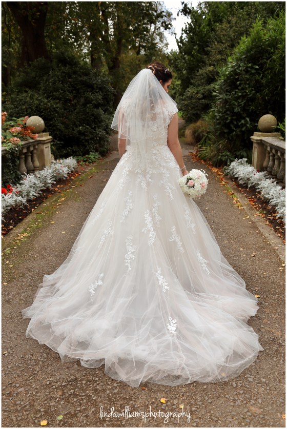 A photograph of the back of a bride's wedding dress in Dewstow Gardens