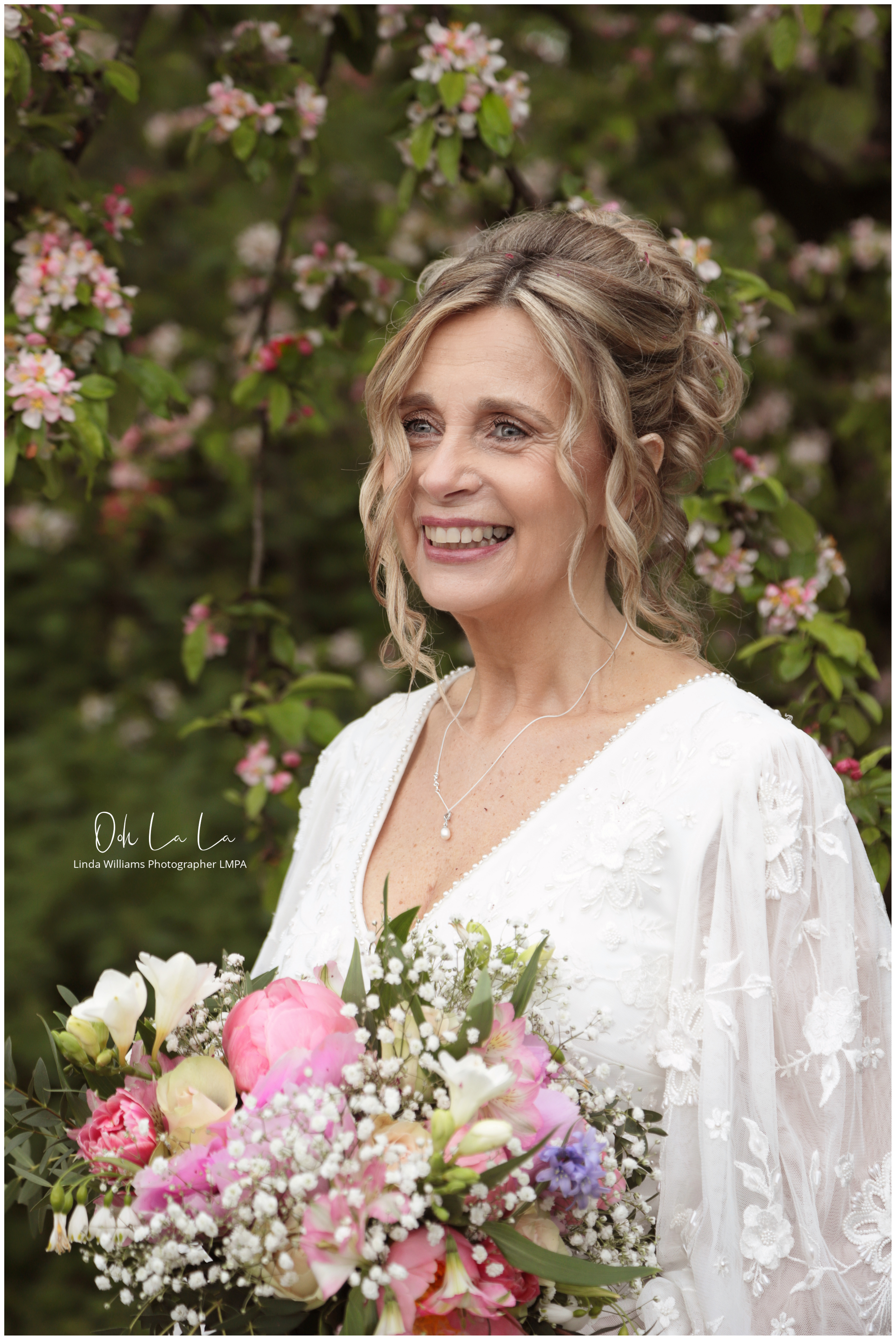 beautiful bride laughing with pink peonies and pink spring blossom