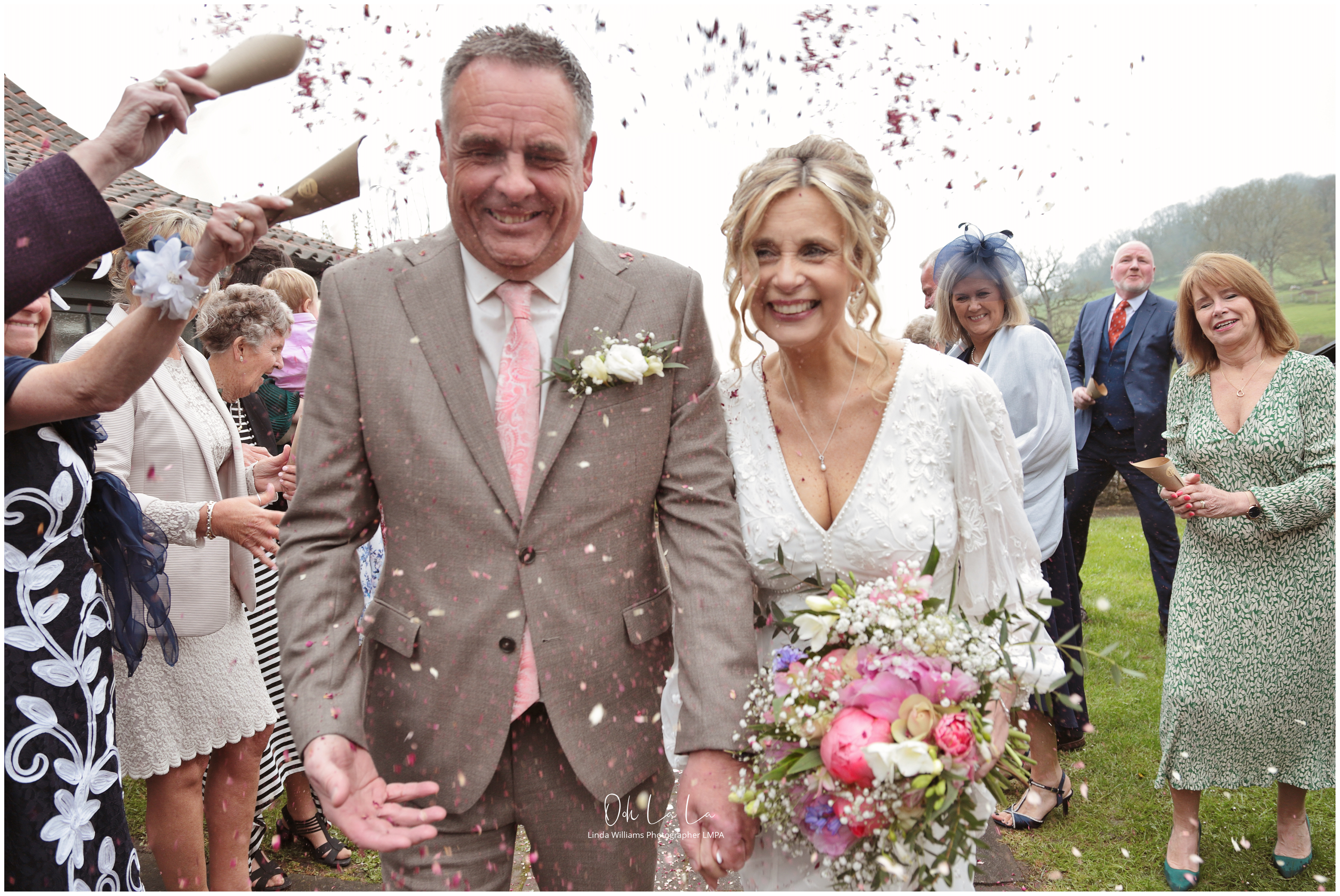 bride and groom grimacing and laughing as confetti is thrown