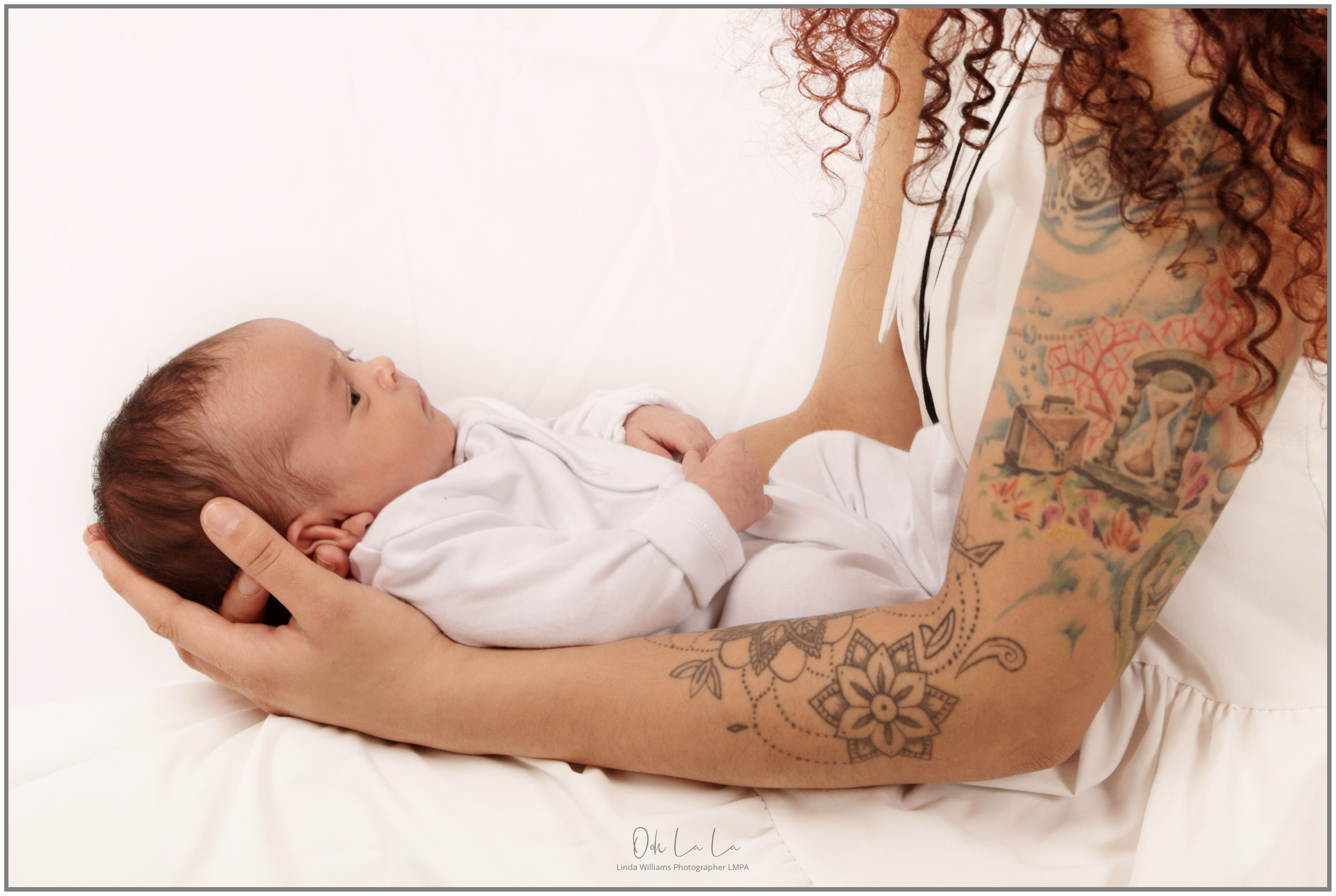 mother holding her newborn baby with tattoos on her arms