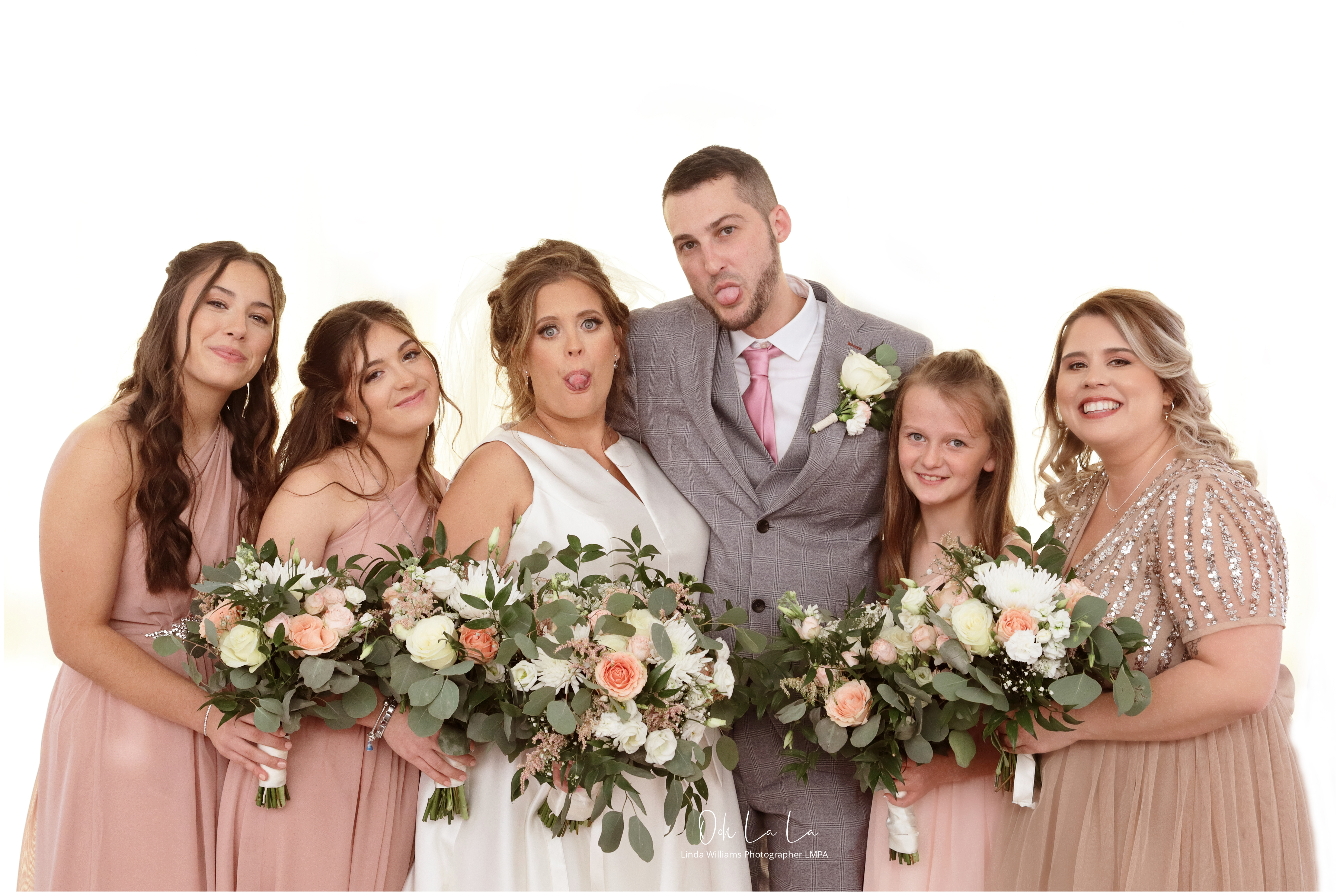 fun shot of bride and groom poking tongues out bridesmaids smiling