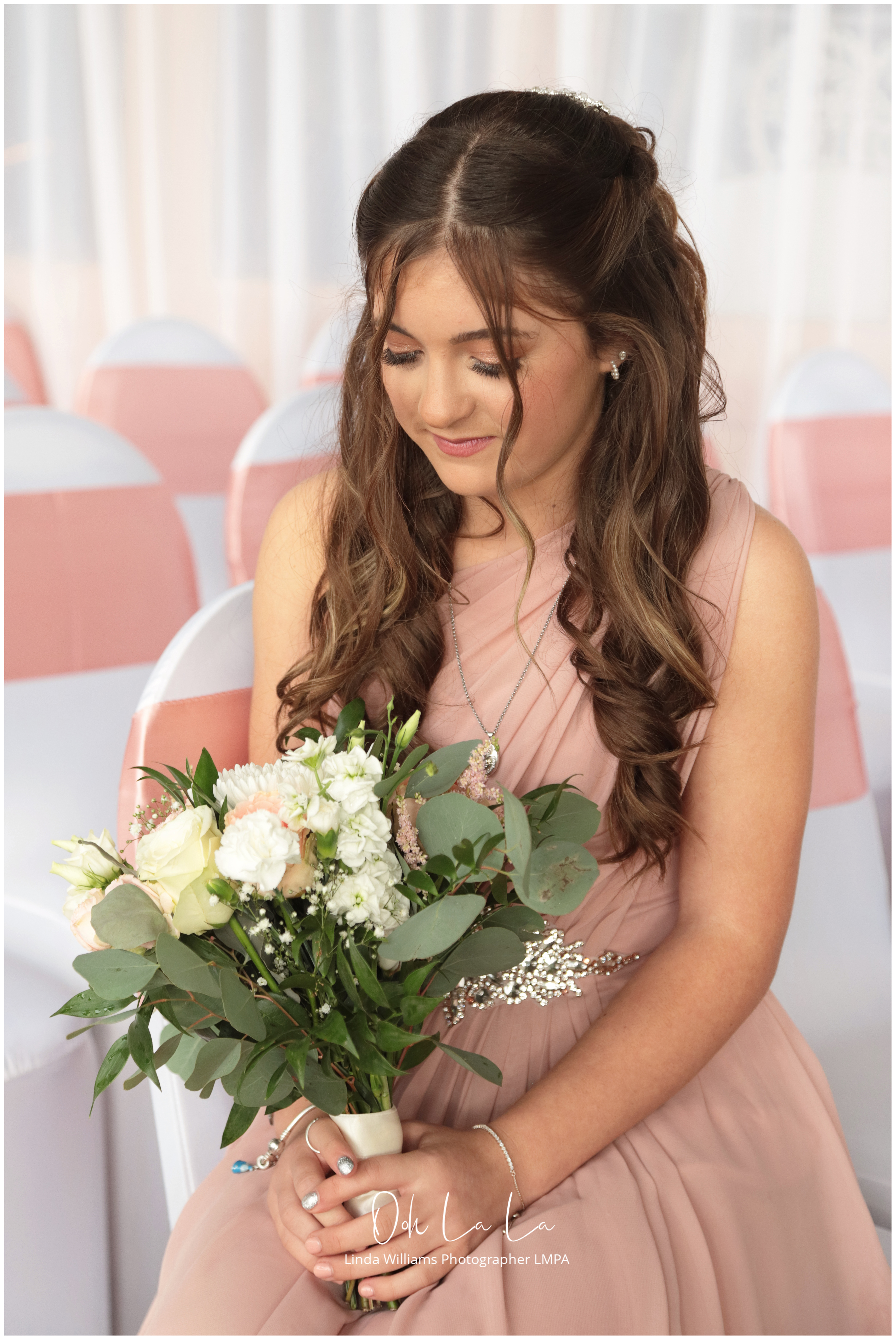 bridesmaid in pink looking down at bouquet
