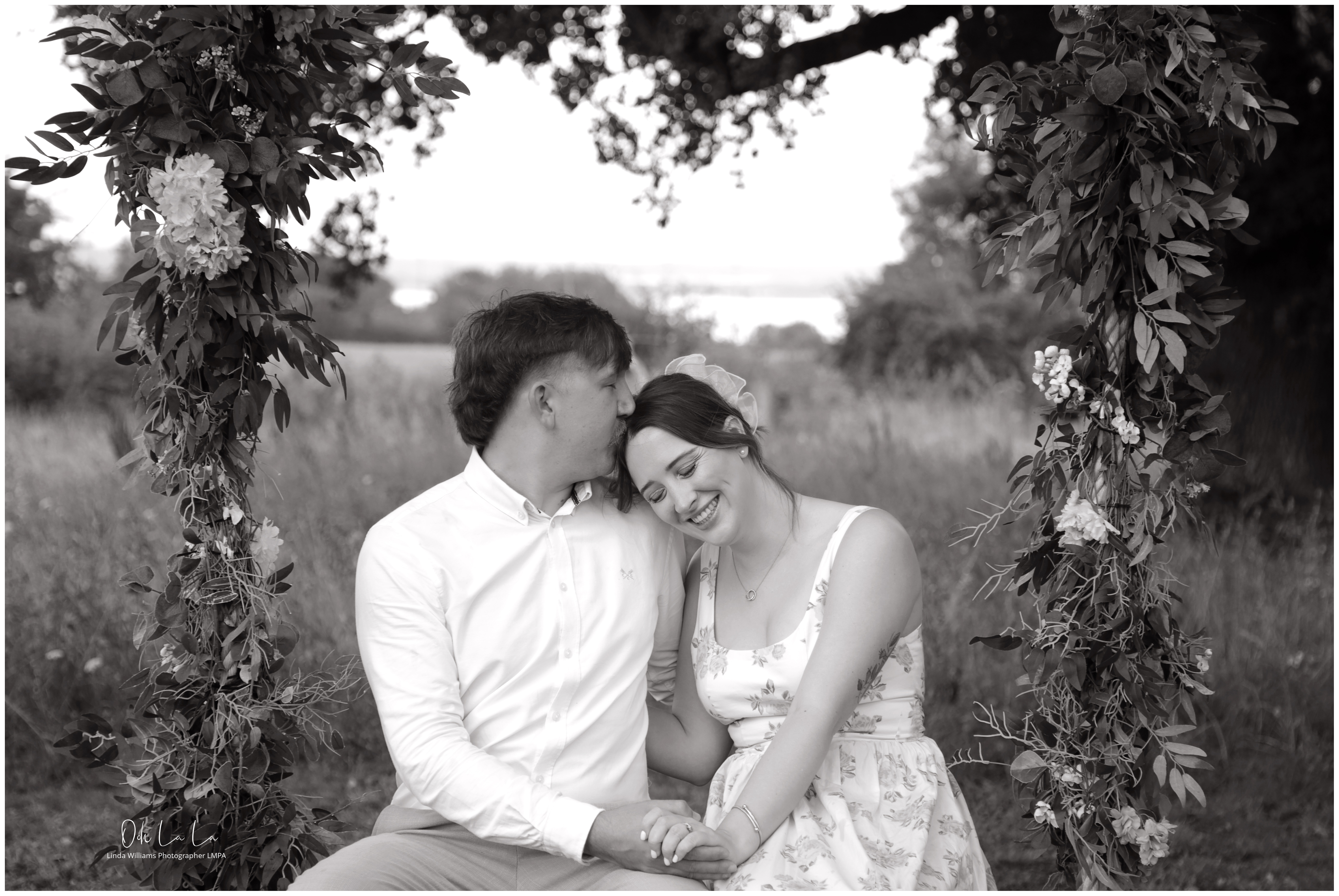 black and white image of young couple on a swing