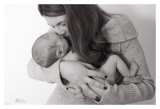 black and white shot of young mum kissing her new born baby