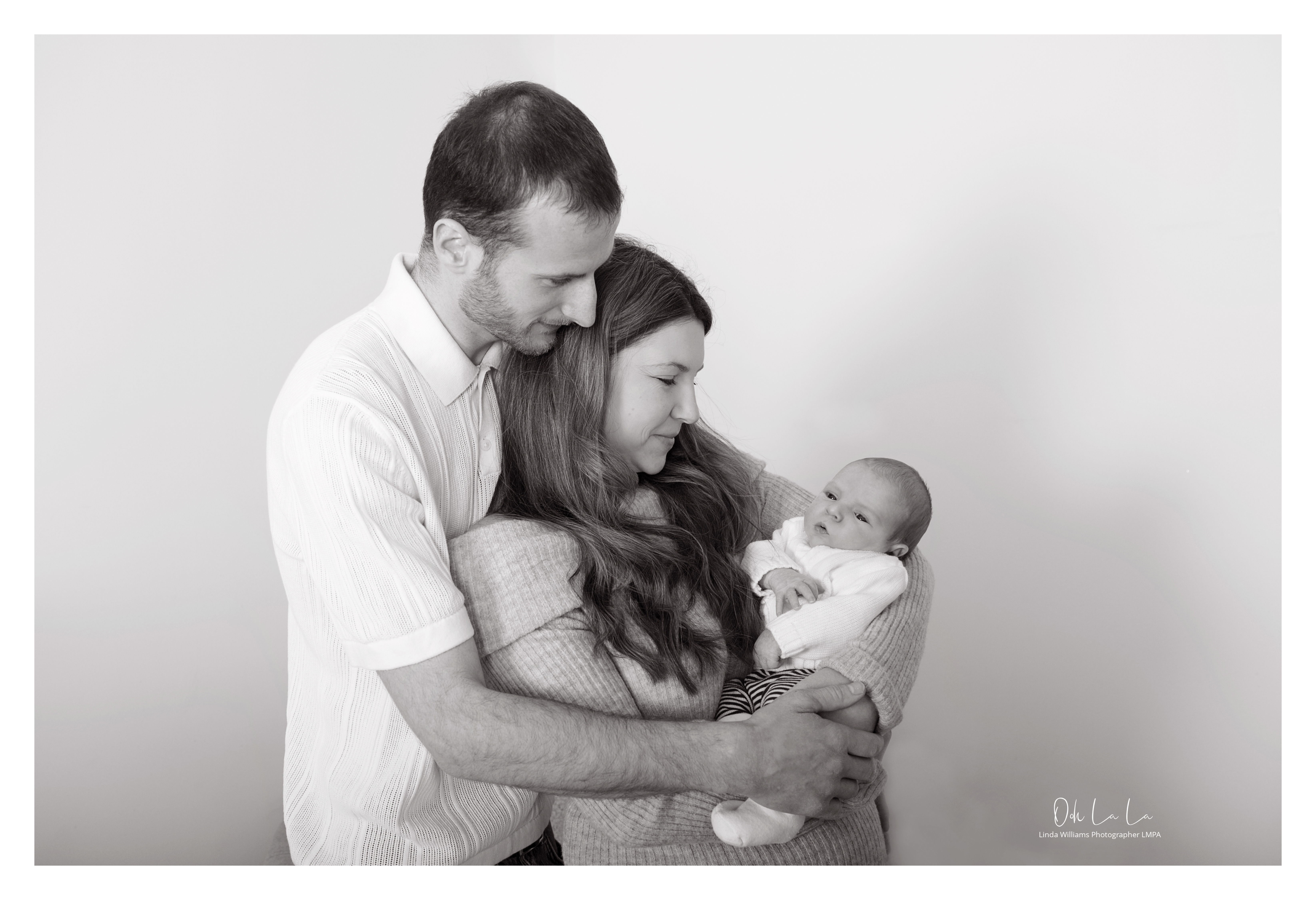 black and white photo of young couple holding their new born baby